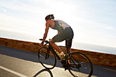 Male triathlete cyclist cycling on ocean road