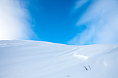 Snow-covered hill under blue sky