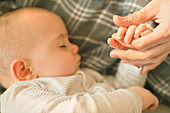 Sleeping baby boy holding hands with father