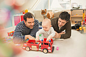 Male gay parents and baby son playing