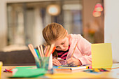 Focused girl drawing, doing crafts at table