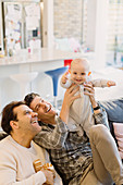 Portrait playful baby son with male gay parents
