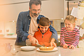 Father cutting and serving pie to children
