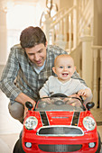 Father pushing happy, baby son in toy car