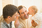 Affectionate baby son kissing male gay parents