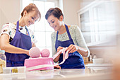 Female caterers finishing pink wedding cake