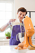 Smiling woman baking, using stand mixer