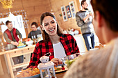 Woman smiling at friend, eating at cabin table