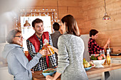 Friends toasting beer bottles in cabin kitchen