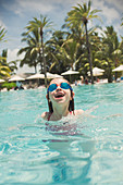 Playful girl swimming with swim goggles