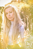 Portrait serious, blonde teenage girl in field