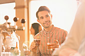 Smiling man sampling beer at bar