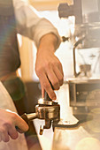 Barista pressing espresso, using espresso machine