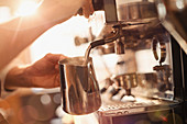 Barista using espresso machine milk frother