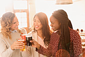 Women friends toasting beer glasses in bar