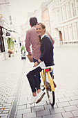 Woman riding on back of boyfriend's bicycle