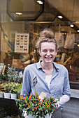 Smiling female florist holding potted plant