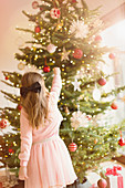 Girl hanging ornaments on Christmas tree
