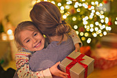 Daughter with Christmas gift hugging mother