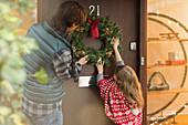 Father and daughter hanging Christmas wreath