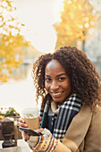 Young woman drinking coffee and texting