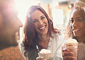 Young woman drinking milkshake with friends