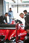 Formula one driver watching pit crew working