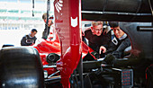Pit crew mechanics examining race car