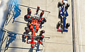 Overhead pit crew replacing tires on race car