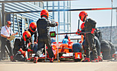 Pit crew replacing tires on formula one race car