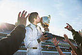 Formula one racing team and driver kissing trophy