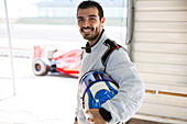 Male formula one race car driver holding helmet