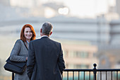 Businessman and businesswoman talking at railing