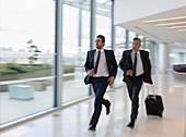 Businessmen running with suitcase in airport