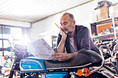 Senior motorcycle mechanic reviewing manual