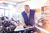 Senior male motorcycle mechanic reviewing plans