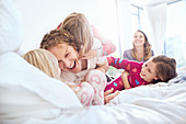 Playful father and daughters tickling on bed