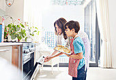 Mother and son baking, placing cookies in oven