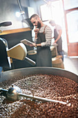 Male coffee roaster behind roasting coffee beans