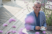 Portrait senior man drinking coffee on sunny patio