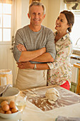 Smiling couple hugging, baking in kitchen