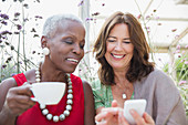 Smiling mature women friends drinking coffee