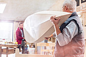 Male carpenters carrying wood boat