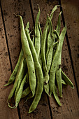 Fresh, rustic, dirty green bean pods on wood