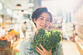 Portrait woman holding fresh kale in market