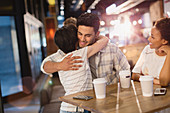 Young couple hugging, drinking coffee in cafe