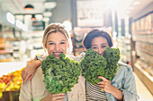 Lesbian couple holding fresh kale in market