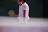 Male tennis doubles talking on sunny tennis court