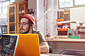 Male designer working at laptop in workshop