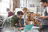 Designers brainstorming at laptop in workshop